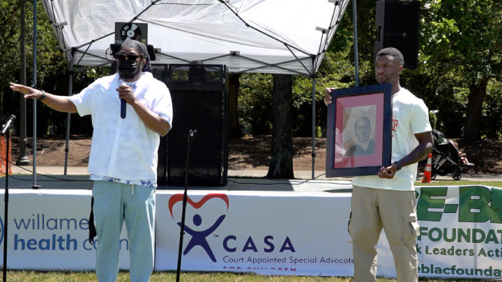 outside with two black men in white shirts speaking