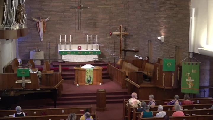 Church auditorium with an alter, pulpit, organ and brick wall background with a Jesus statue on it.