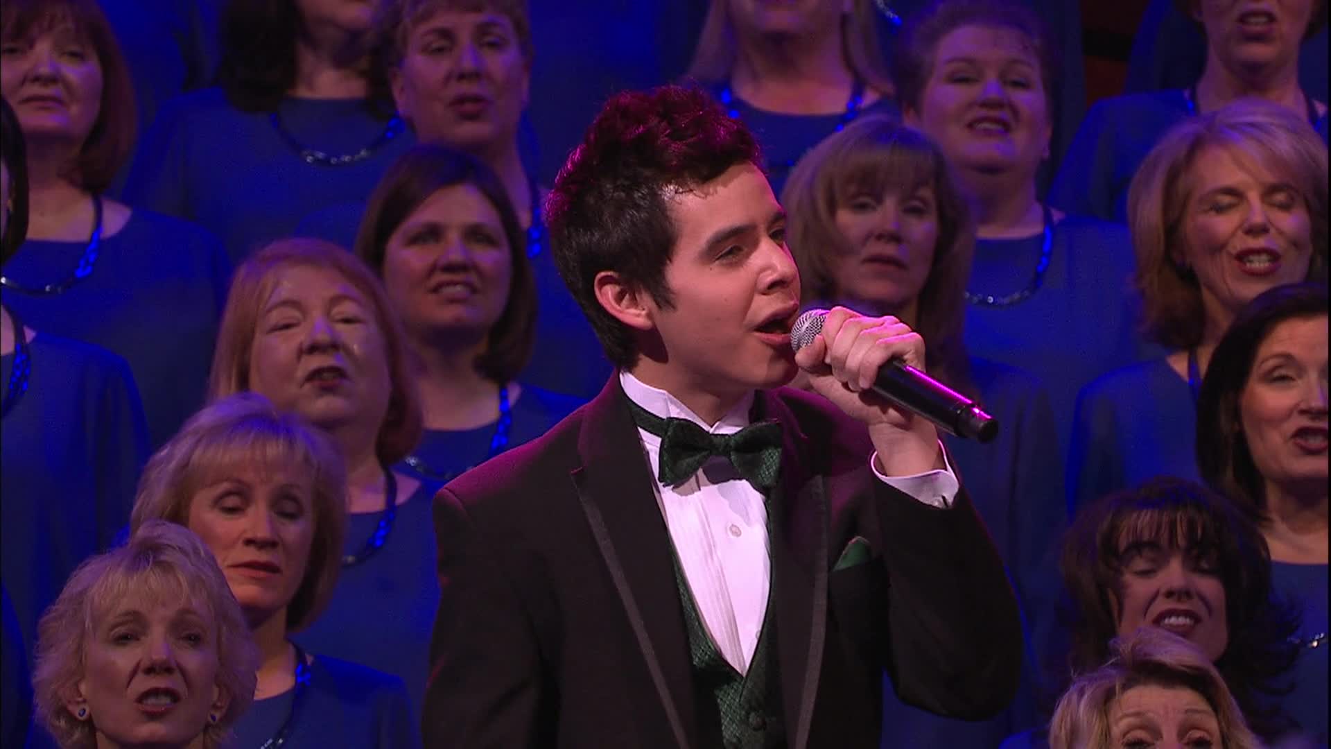 Man in a tux singing in front of a choir