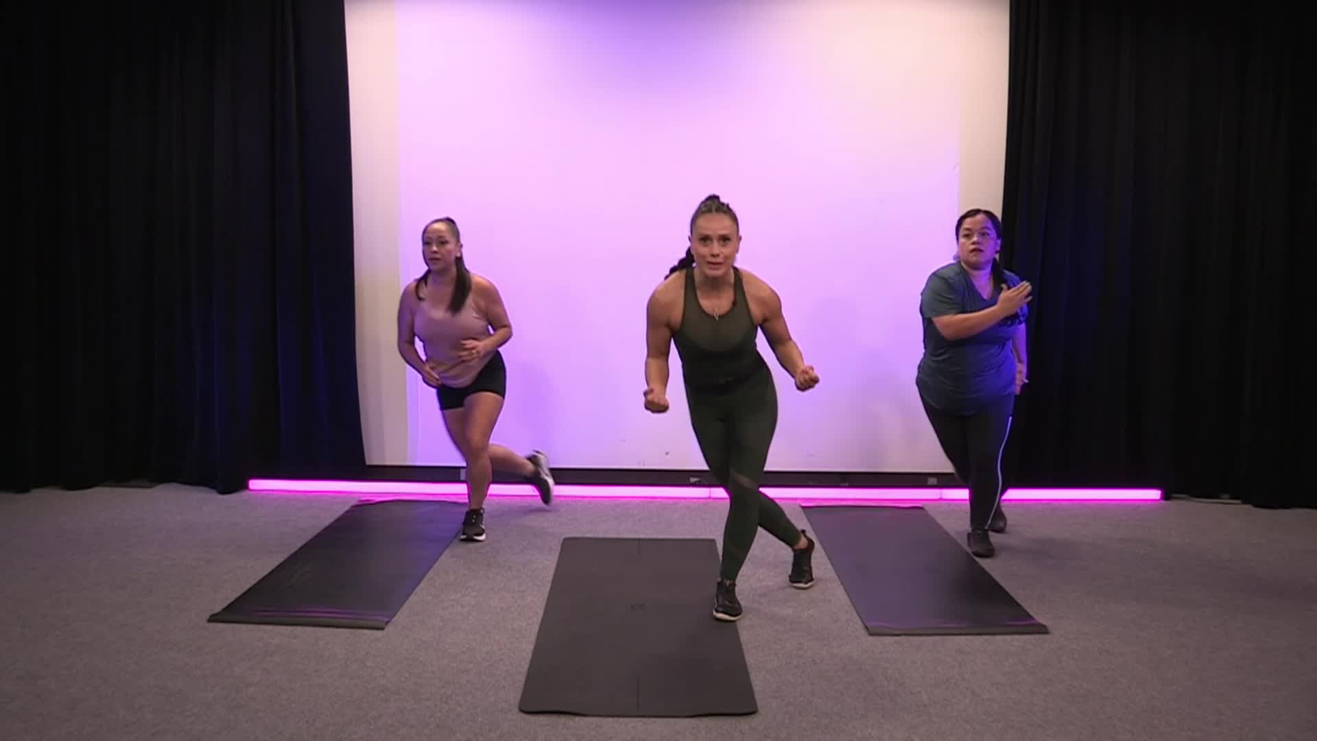 Purple lighted background with three people doing exercises